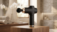 Pistola de masaje muscular recargable, vista de detalle en ambiente de baño cálido